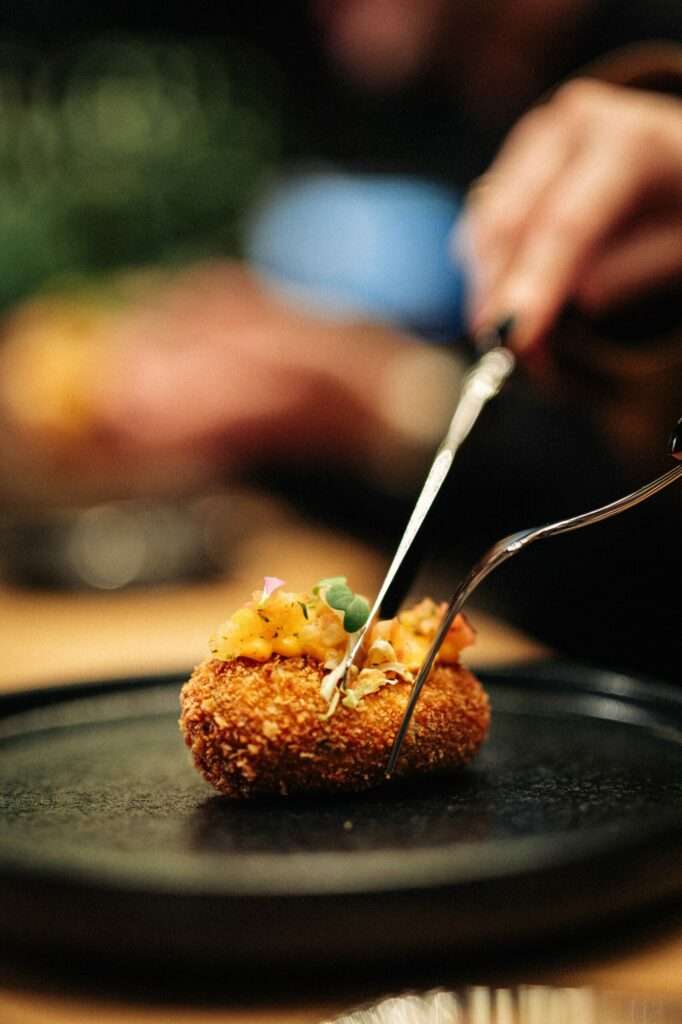 Crab cake with pineapple chutney and bang-bang mayo is cut with cutlery